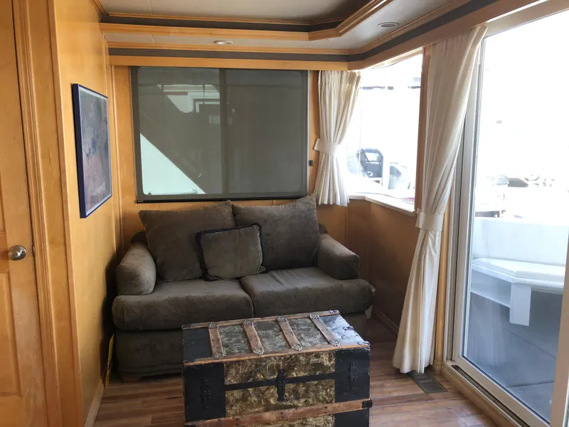 Slide: The Image of Cozy living area in a 2005 Custom boat, featuring a sofa, trunk table, and large windows. - 20