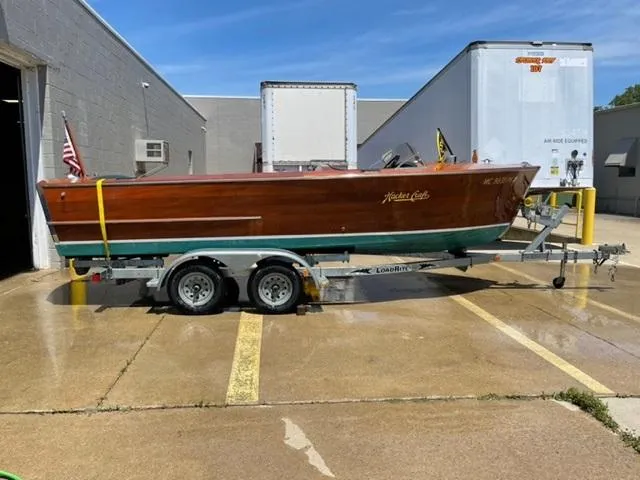 Slide: The Image of 1949 Hacker-Craft Utility boat on trailer, parked outside industrial building. - 2