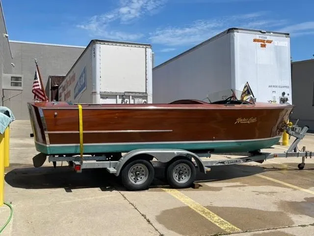 Slide: The Image of 1949 Hacker-Craft Utility boat on trailer, parked outdoors near industrial buildings. - 5