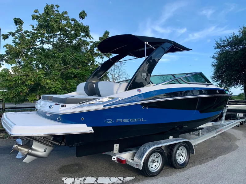 Slide: The Image of 2016 Regal Fastrac boat on a trailer, blue and black exterior, parked outdoors. - 18