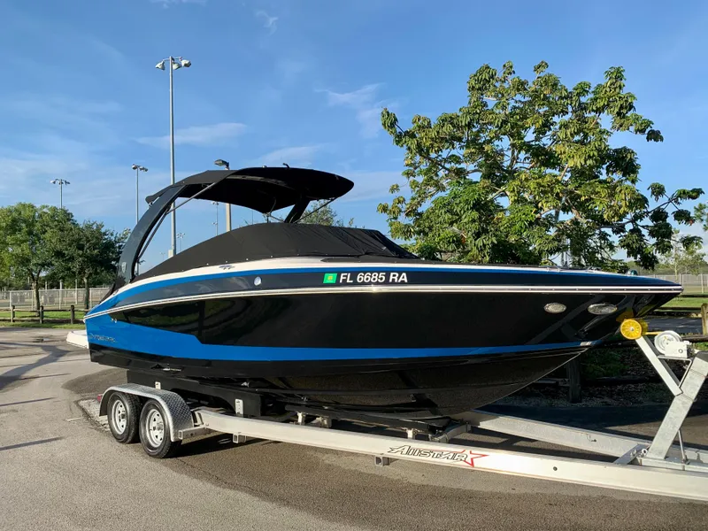 Slide: The Image of 2016 Regal Fastrac boat on trailer, black with blue stripe, parked outdoors. - 3