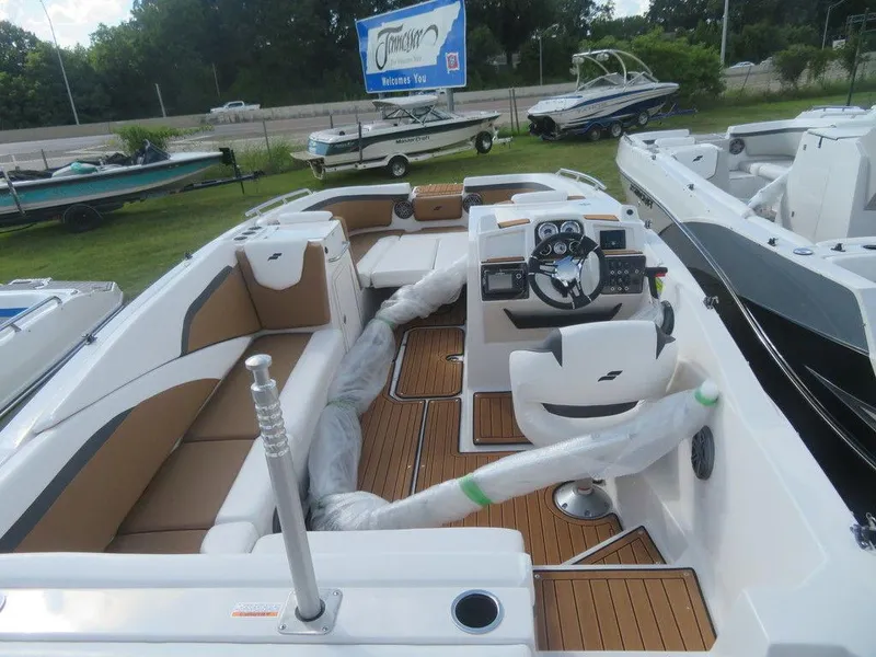 Slide: The Image of 2023 Starcraft SVX OB 231 OB boat interior with tan and white seating, steering console, and wood flooring. - 6