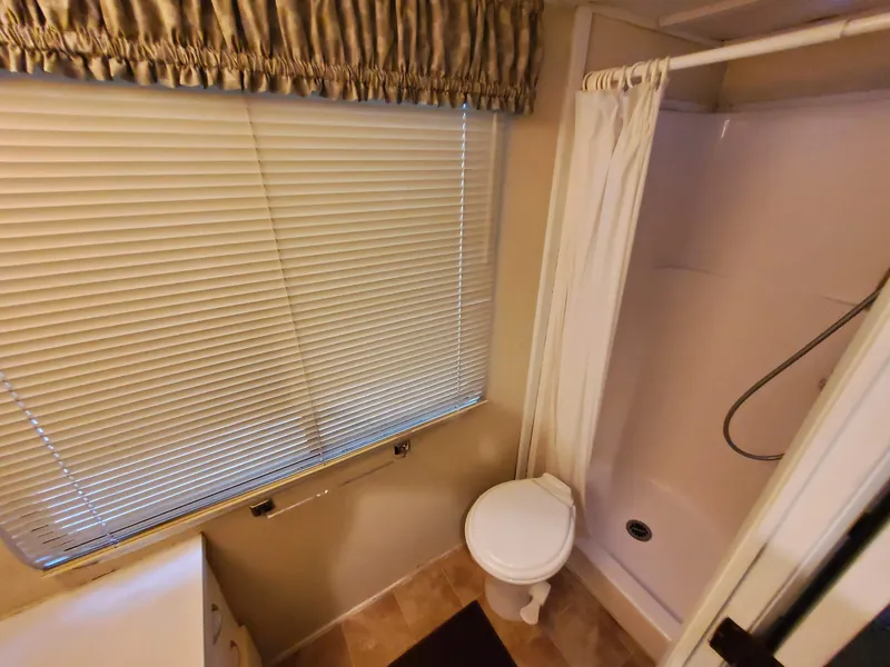 Slide: The Image of Bathroom in a 1995 Skipperliner 55x15 Houseboat with shower, toilet, and window blinds. - 14