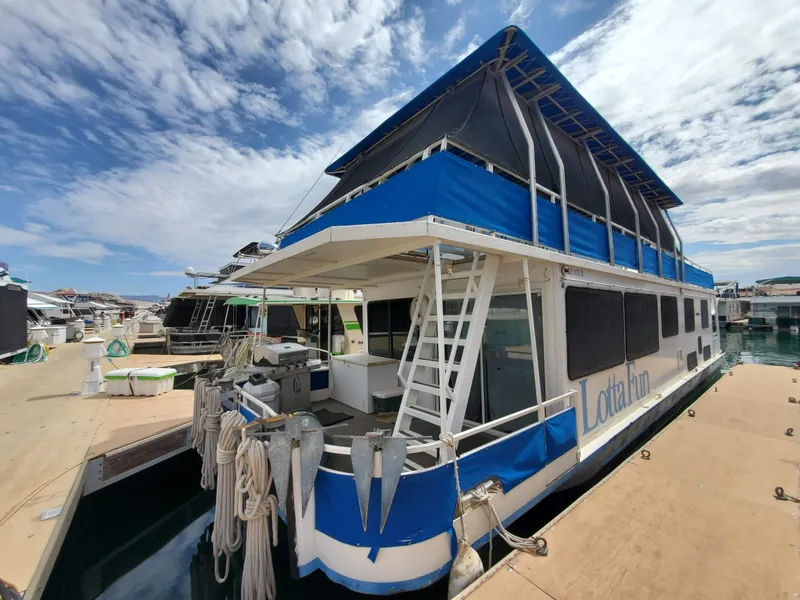 Slide: The Image of 1995 Skipperliner 55x15 Houseboat docked at a marina under a partly cloudy sky. - 2