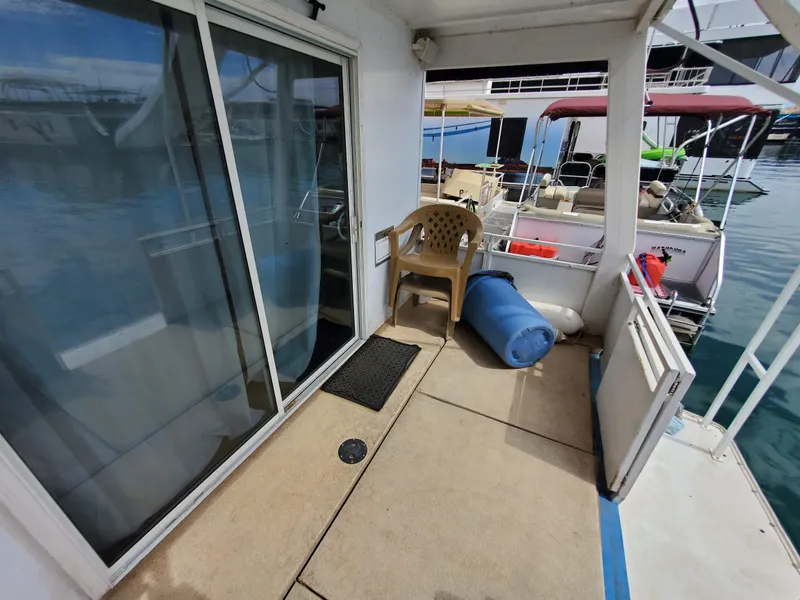 Slide: The Image of 1995 Skipperliner 55x15 Houseboat deck with sliding glass door and outdoor seating. - 26