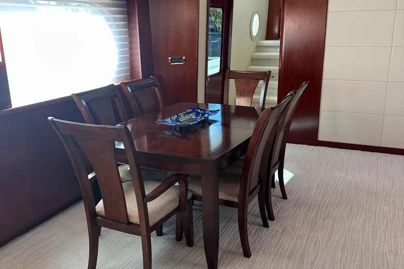 Slide: The Image of Elegant dining area on 2015 Broward Raised Pilothouse M/Y yacht with wooden table and chairs. - 26