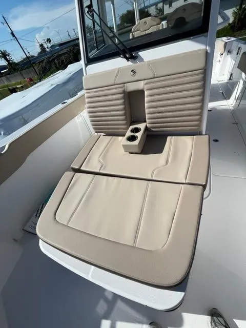 Slide: The Image of 2023 Edgewater 340CC boat with beige cushioned seating and cup holders. - 17