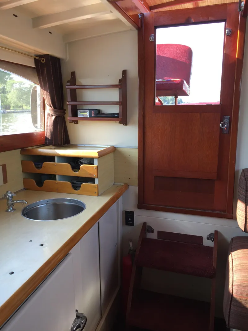Slide: The Image of 1954 Chris-Craft Commander interior with wooden cabinetry, sink, and stairs leading to deck. - 15