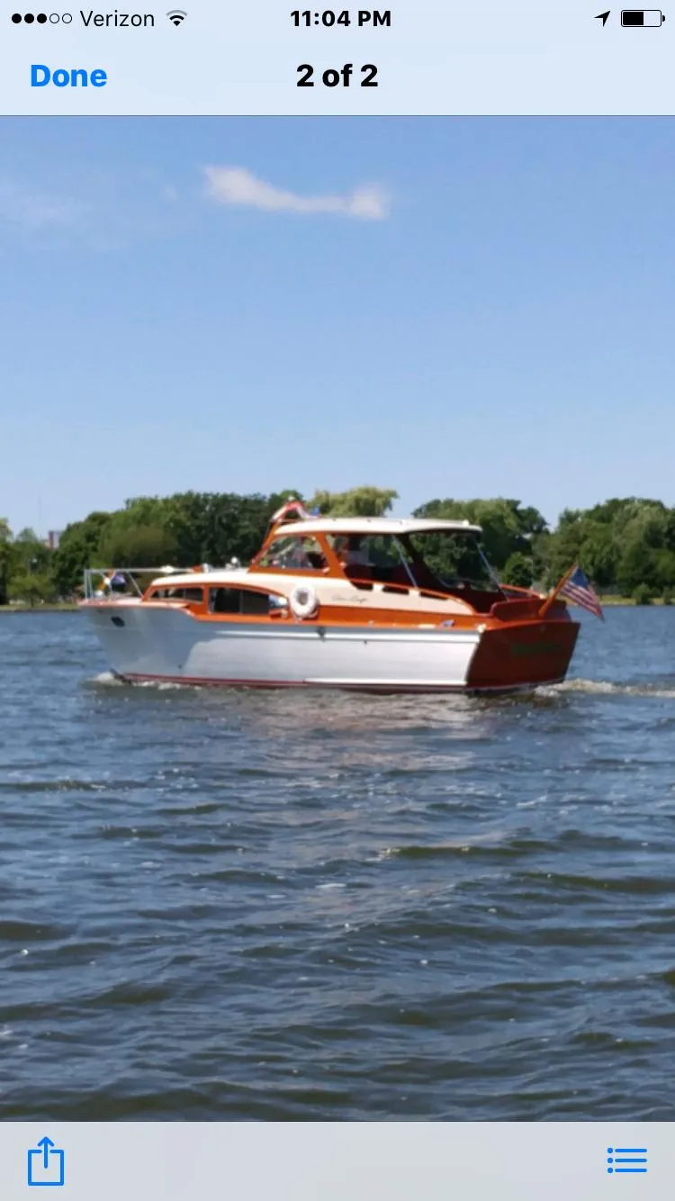 Slide: The Image of 1954 Chris-Craft Commander boat cruising on a lake under a clear blue sky. - 2