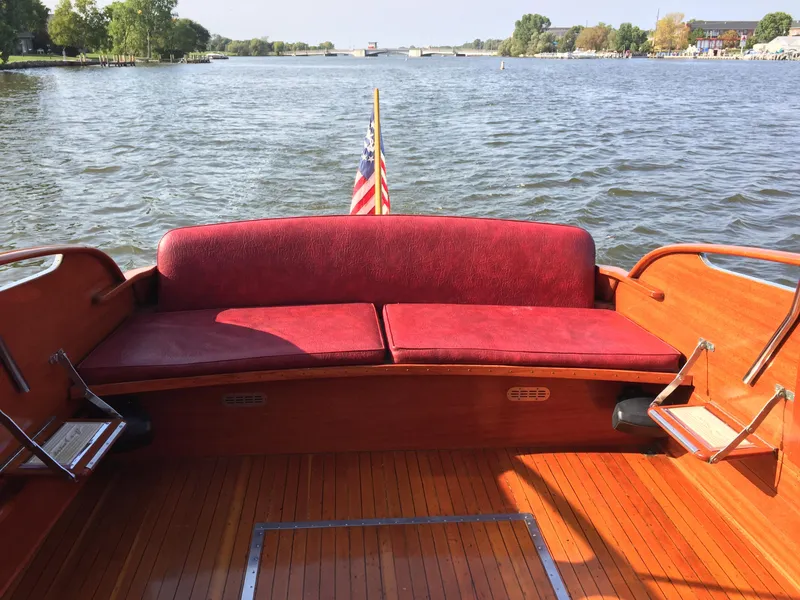 Slide: The Image of 1954 Chris-Craft Commander boat with red seating, wooden deck, and American flag on a serene lake. - 22