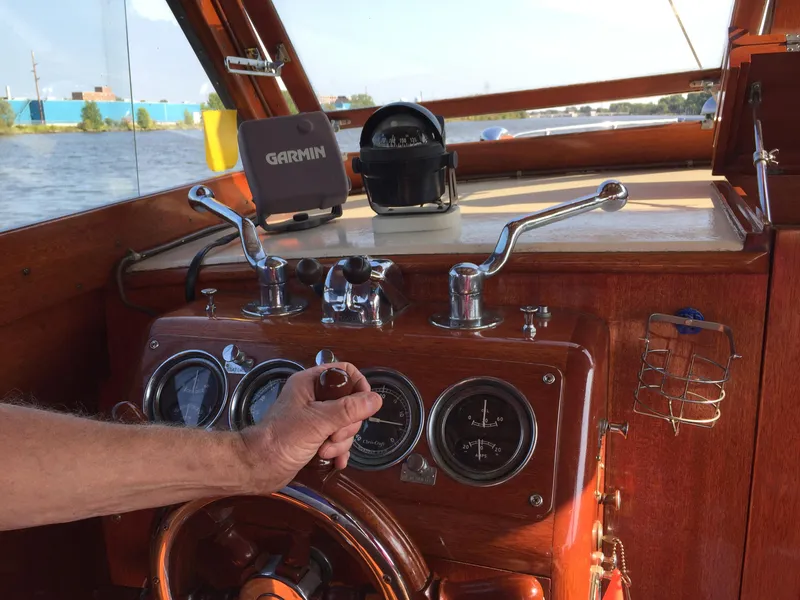 Slide: The Image of 1954 Chris-Craft Commander boat dashboard with Garmin device, wooden steering wheel, and gauges. - 25