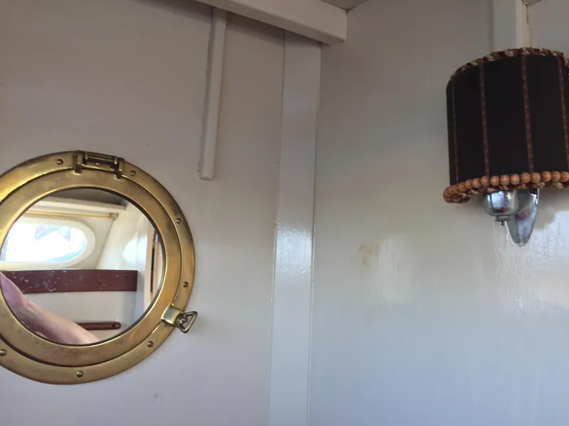 Slide: The Image of 1954 Chris-Craft Commander interior with brass porthole and vintage wall lamp. - 6