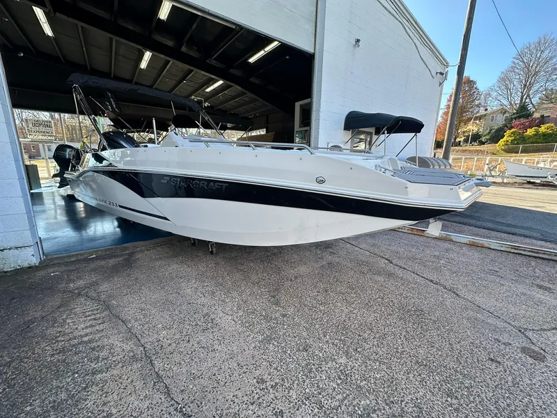 Slide: The Image of 2025 Starcraft SVX 211 OB boat in showroom, sleek design, black and white exterior. - 2