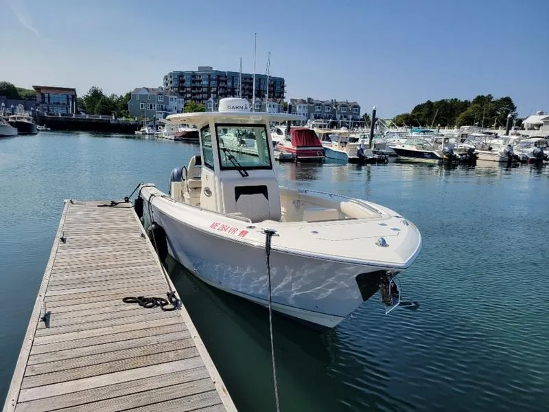 Slide: The Image of 2023 Sailfish 272 CC boat docked in a marina with surrounding boats and buildings. - 14