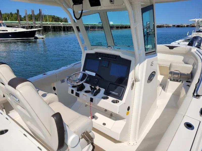 Slide: The Image of 2023 Sailfish 272 CC boat interior with modern helm and seating on calm water. - 7