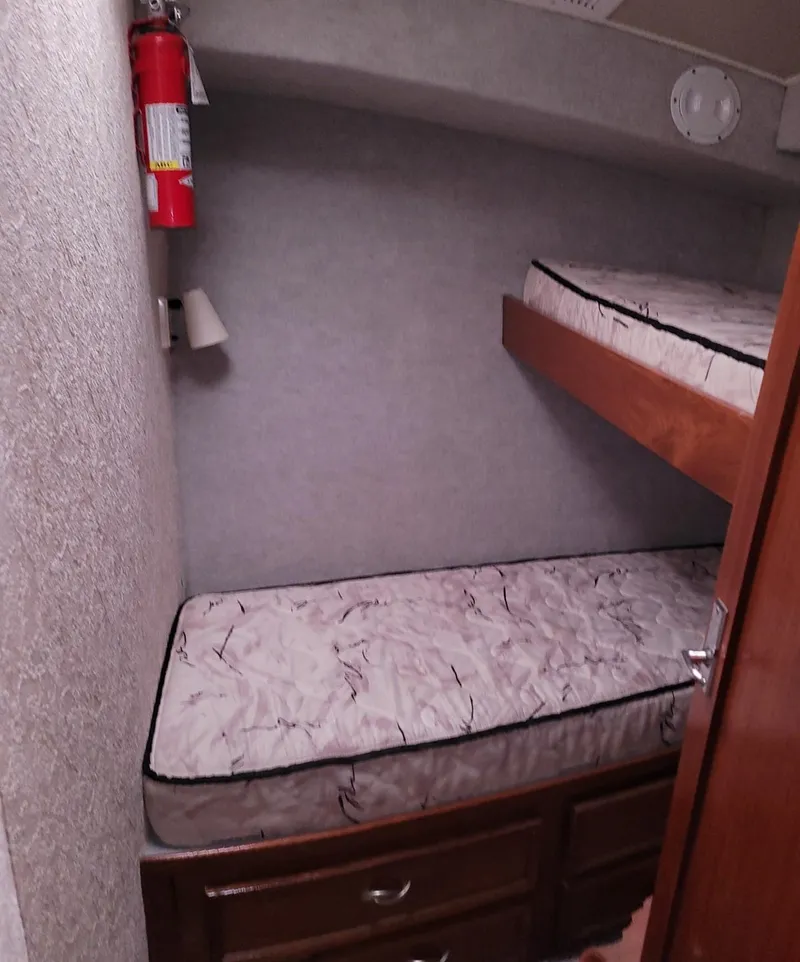 Slide: The Image of 1983 Ocean Yachts Super Sport cabin with bunk beds and fire extinguisher. - 14