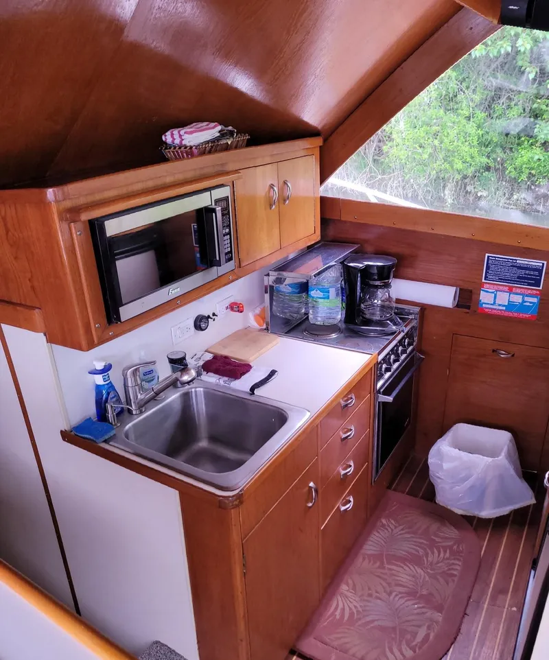 Slide: The Image of 1983 Ocean Yachts Super Sport kitchen with sink, stove, microwave, and wooden cabinetry. - 8