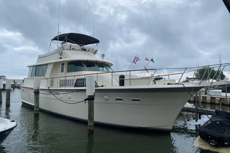 The Image of 1983 Hatteras 53 Extended Deckhouse Motor Yacht docked under cloudy skies. - 1