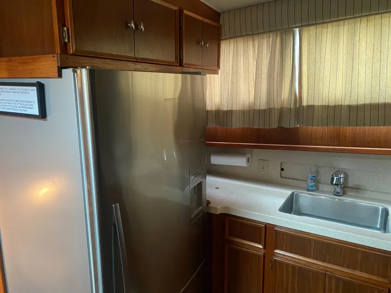 Slide: The Image of Kitchen area of 1983 Hatteras 53 Motor Yacht with stainless steel fridge and wooden cabinets. - 13