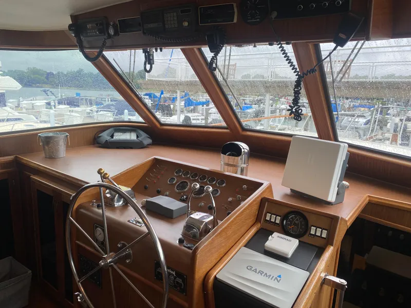 Slide: The Image of 1983 Hatteras 53 Motor Yacht helm with steering wheel, navigation equipment, and marina view. - 2