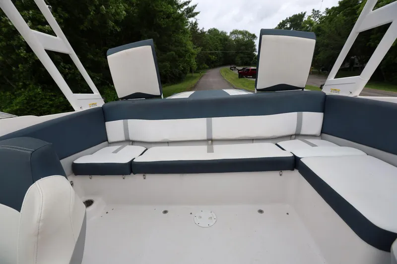 Slide: The Image of 2015 Four Winns H200 boat interior with white and blue seating, surrounded by greenery. - 10