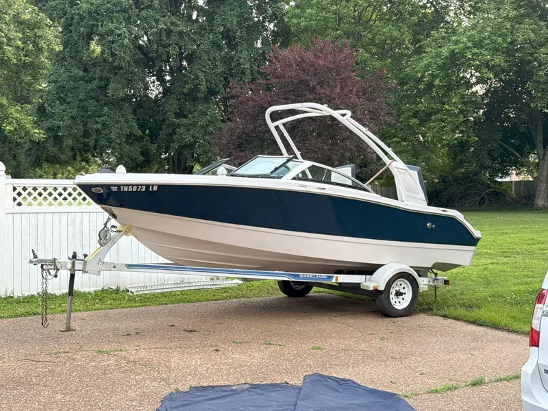 Slide: The Image of 2015 Four Winns H200 boat on trailer, parked in a driveway with lush greenery. - 3