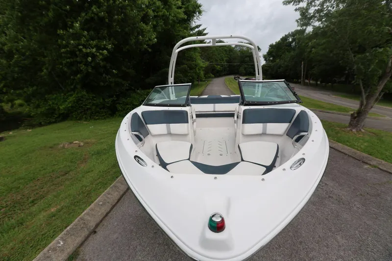 Slide: The Image of 2015 Four Winns H200 boat with open bow seating, parked on a tree-lined road. - 5