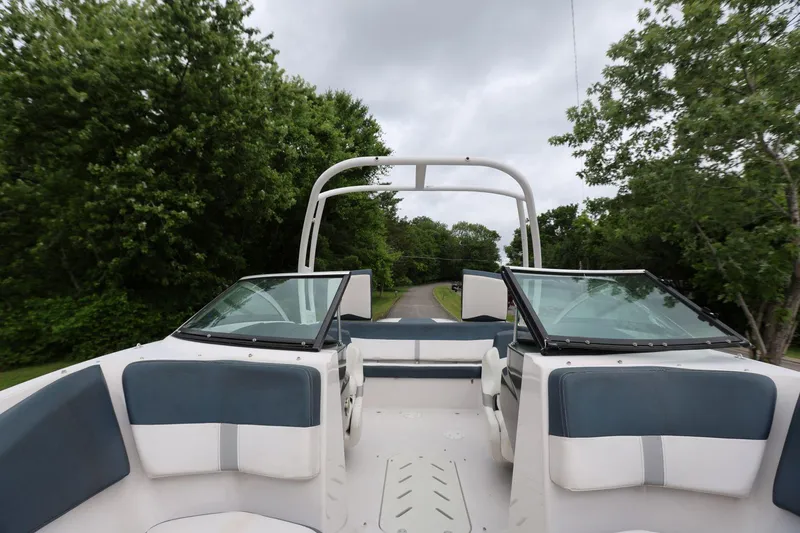 Slide: The Image of 2015 Four Winns H200 boat interior with open seating, surrounded by lush greenery. - 7