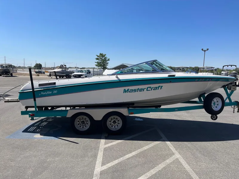 Slide: The Image of 1991 MasterCraft Maristar 210 boat on trailer in parking lot under clear blue sky. - 7