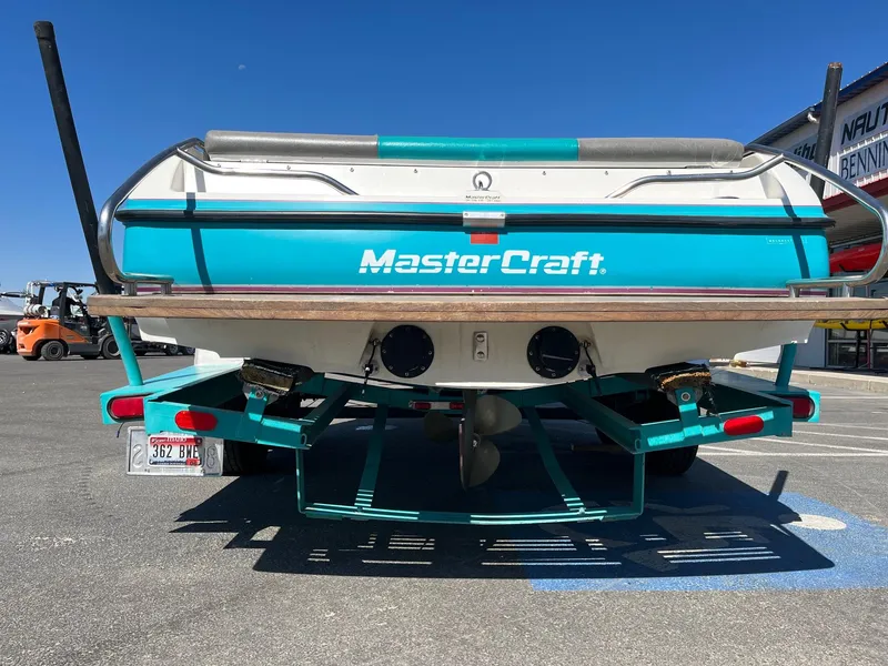 Slide: The Image of 1991 MasterCraft Maristar 210 boat rear view, teal and white, parked on a trailer. - 9
