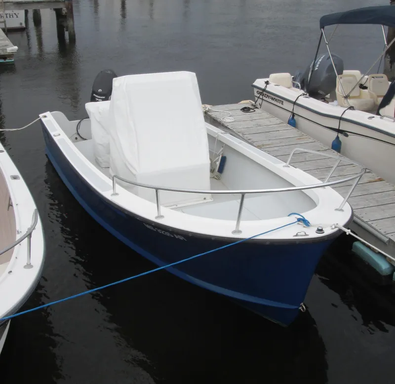 Slide: The Image of 1975 Tripp Center Console boat docked, featuring a blue hull and white interior. - 1