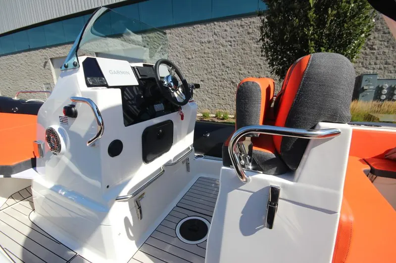 Slide: The Image of 2022 Zodiac Medline 7.5 NEO boat interior with orange seating and control panel. - 2