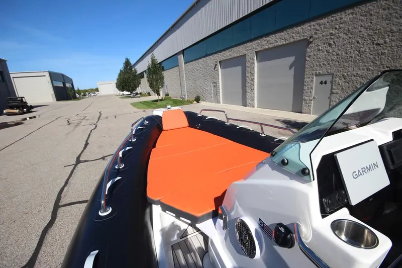 Slide: The Image of 2022 Zodiac Medline 7.5 NEO boat with orange seating, parked near industrial buildings. - 22