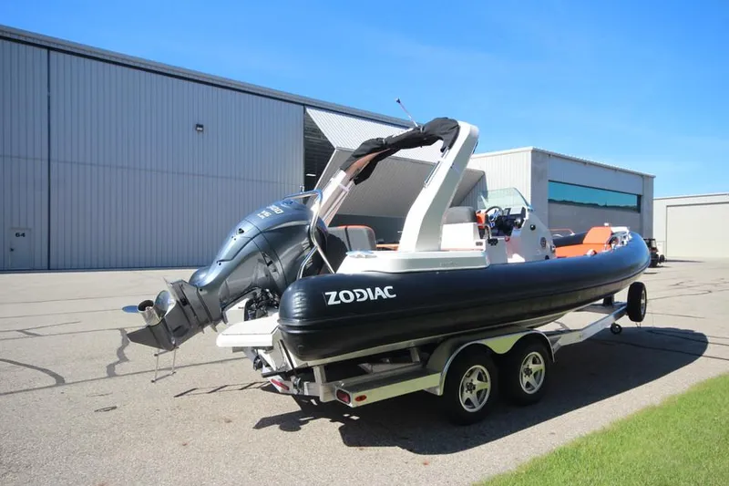 Slide: The Image of 2022 Zodiac Medline 7.5 NEO boat on trailer, parked near a warehouse. - 7