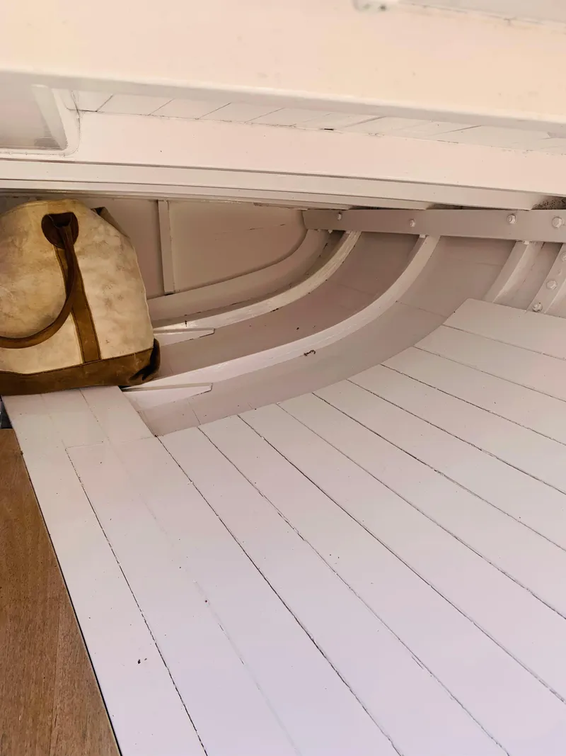 Slide: The Image of Interior of a 1914 Buzzards Bay 25 boat with white wooden planks and a vintage bag. - 12