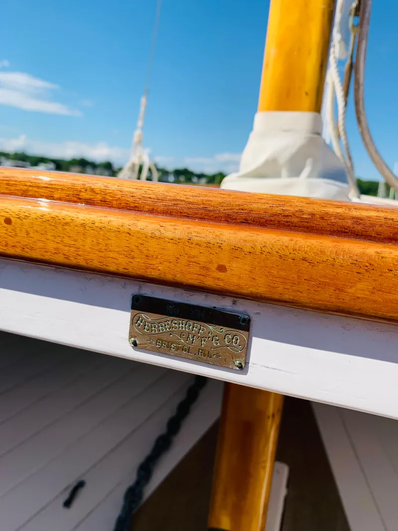 Slide: The Image of Close-up of a 1914 Buzzards Bay 25 sailboat with a wooden mast and brass nameplate. - 21