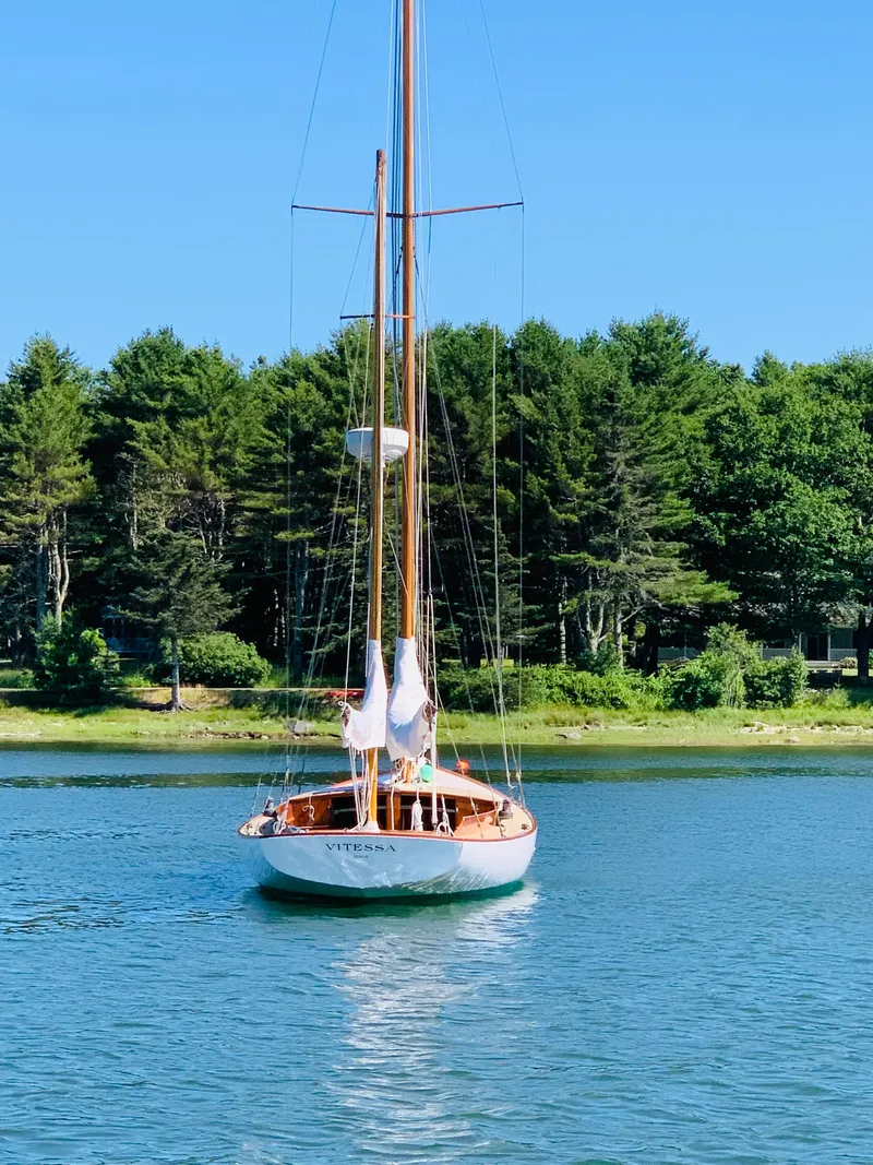 Slide: The Image of Vintage 1914 Buzzards Bay 25 sailboat on a serene lake with forest backdrop. - 3