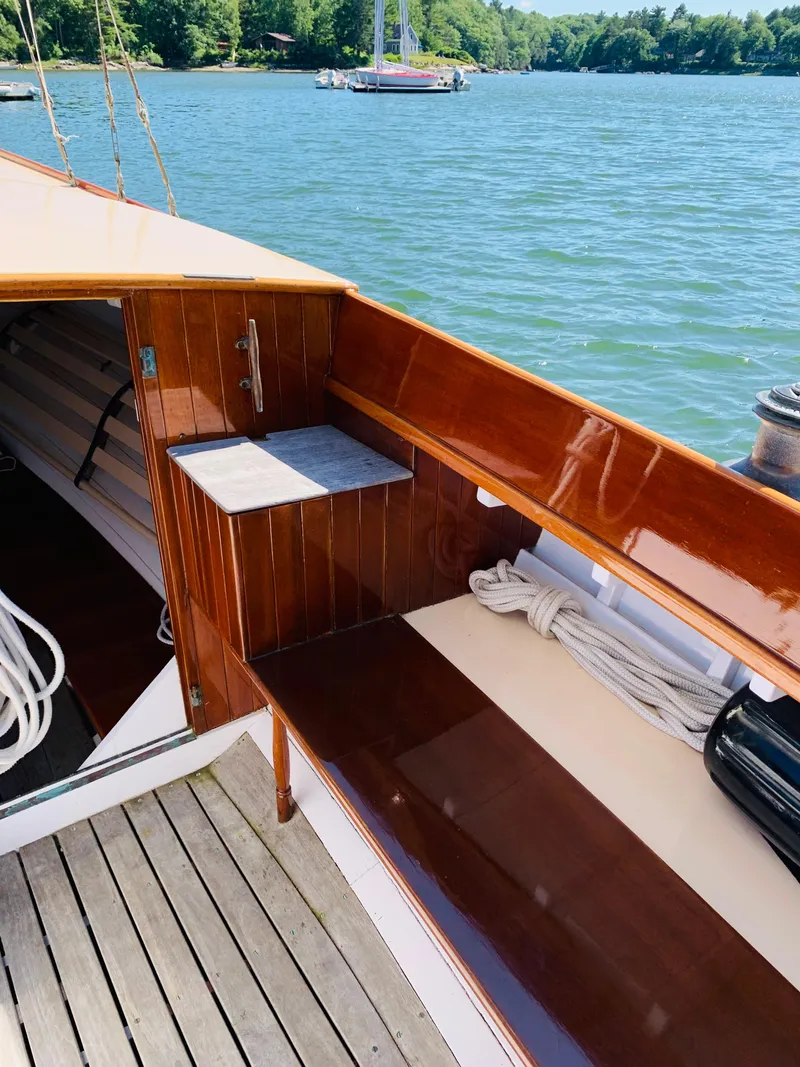 Slide: The Image of 1914 Buzzards Bay 25 sailboat with polished wood interior docked on a serene lake. - 8