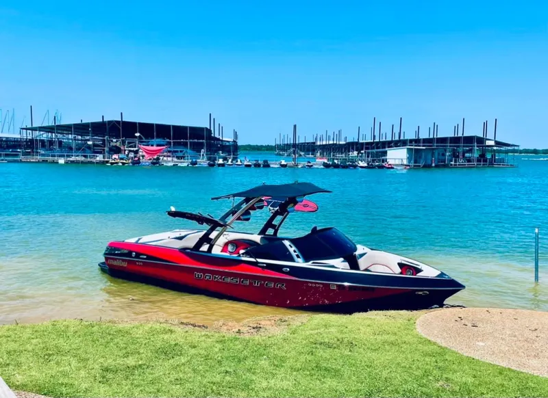 The Image of 2013 Malibu 247LSV boat docked by a marina on a sunny day. - 1