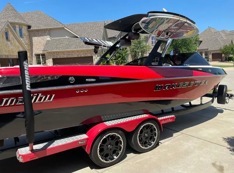 Slide: The Image of 2013 Malibu 247LSV Wakesetter boat on a red and black trailer in a residential driveway. - 8
