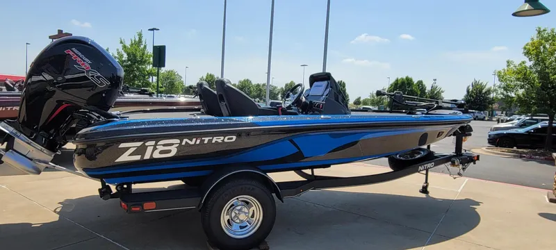 Slide: The Image of 2023 Nitro Z18 boat on trailer, blue and black, parked outdoors. - 1