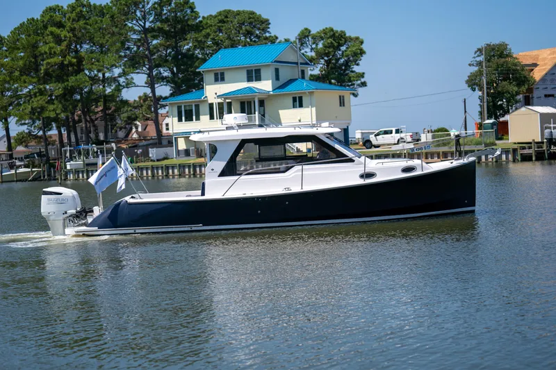 The Image of 2023 True North 34 OE boat cruising on a calm river near waterfront homes. - 0