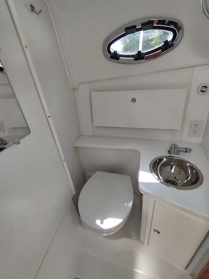 Slide: The Image of Compact bathroom in 2023 True North 34 OE boat with toilet, sink, and porthole window. - 19