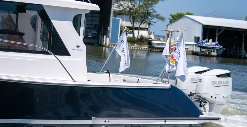 Slide: The Image of 2023 True North 34 OE boat with Suzuki engines, docked near a marina. - 3