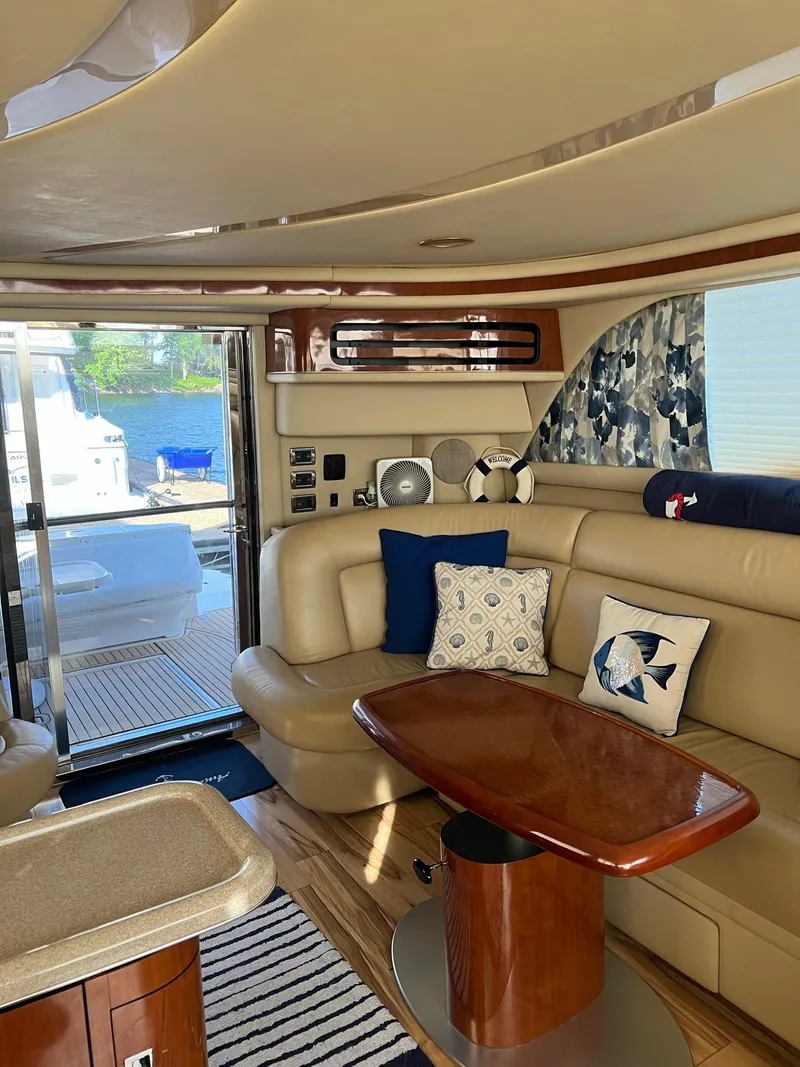 Slide: The Image of Interior of 2003 Sea Ray 480 Sedan Bridge yacht with beige seating and wooden table. - 16
