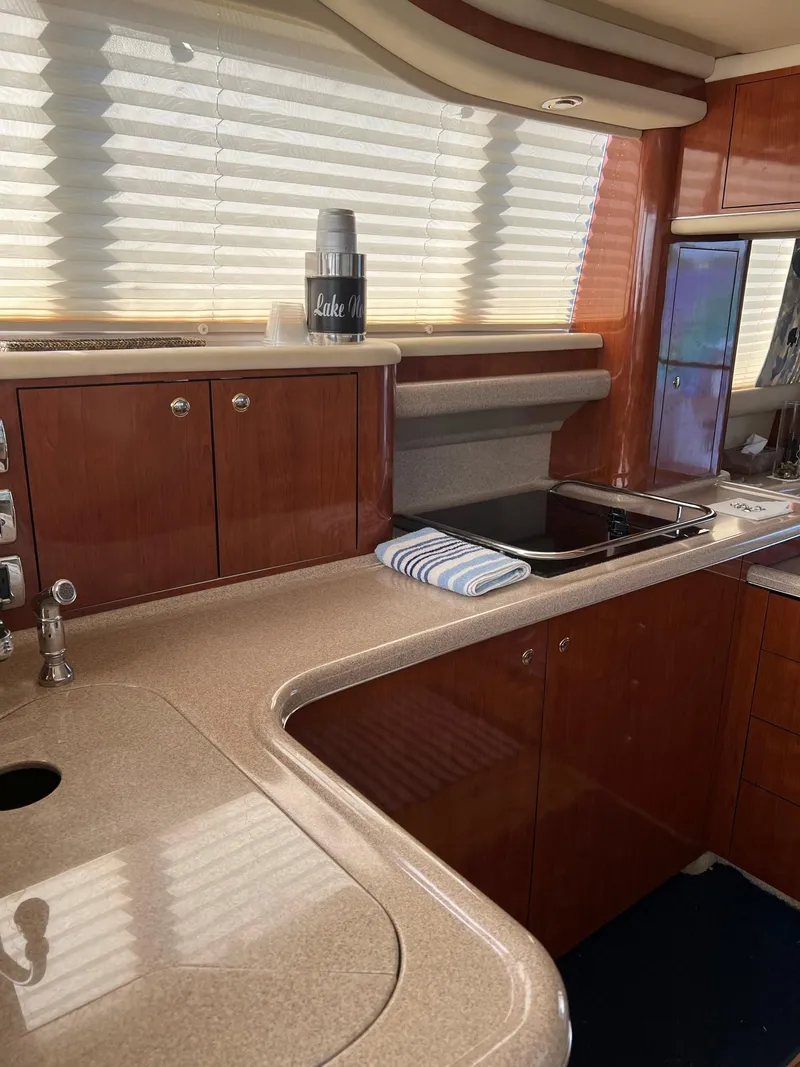 Slide: The Image of 2003 Sea Ray 480 Sedan Bridge kitchen with sleek countertops and wooden cabinetry. - 24