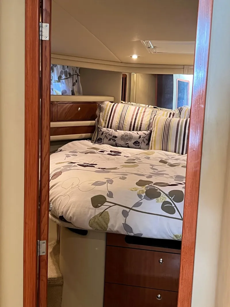 Slide: The Image of 2003 Sea Ray 480 Sedan Bridge bedroom with floral bedding and wooden accents. - 35