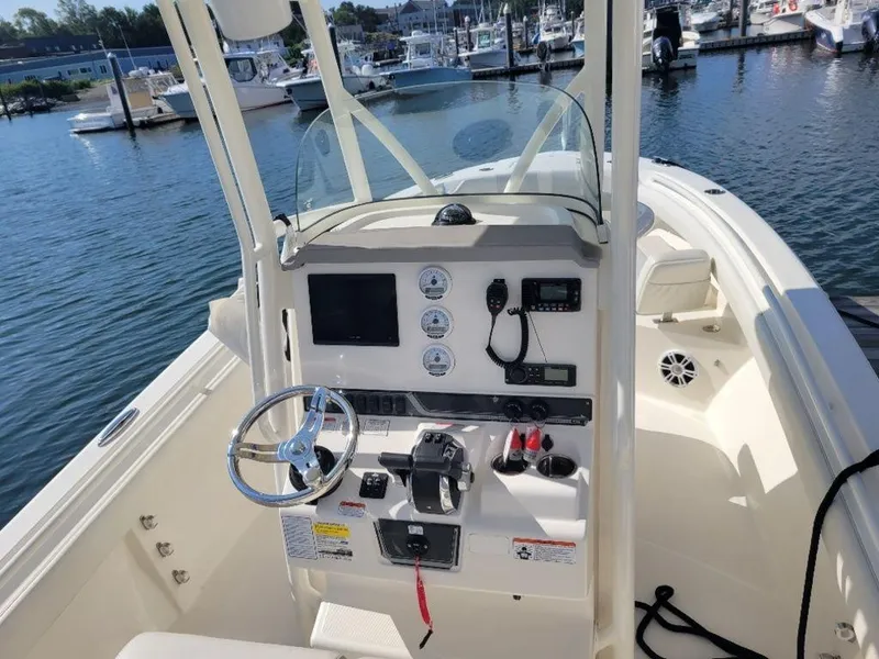 Slide: The Image of 2020 Mako 236 CC Dual console boat at marina, featuring steering wheel and control panel. - 4