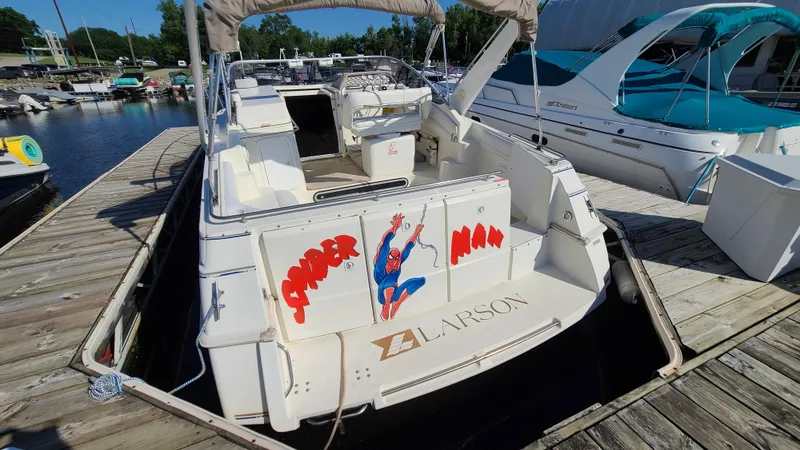 Slide: The Image of 1994 Larson 300 Cabrio boat docked, featuring Spider-Man graphics on the stern. - 5