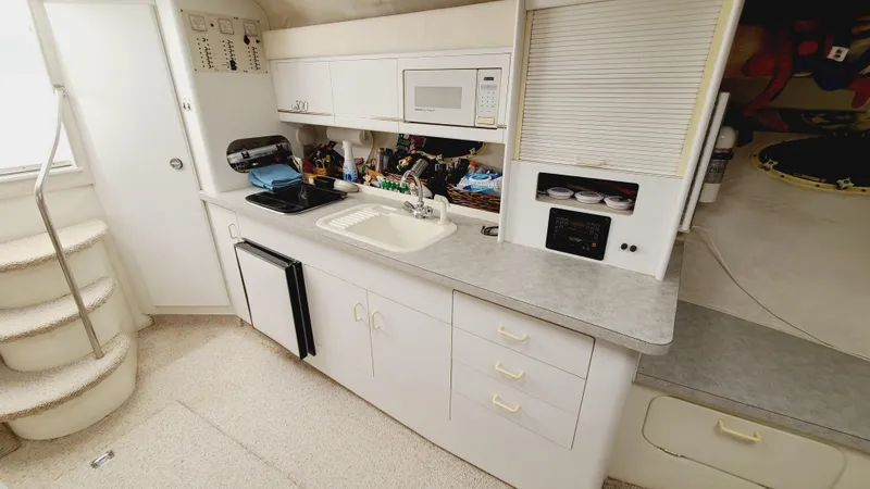 Slide: The Image of 1994 Larson 300 Cabrio boat interior kitchen with sink, microwave, and storage cabinets. - 20
